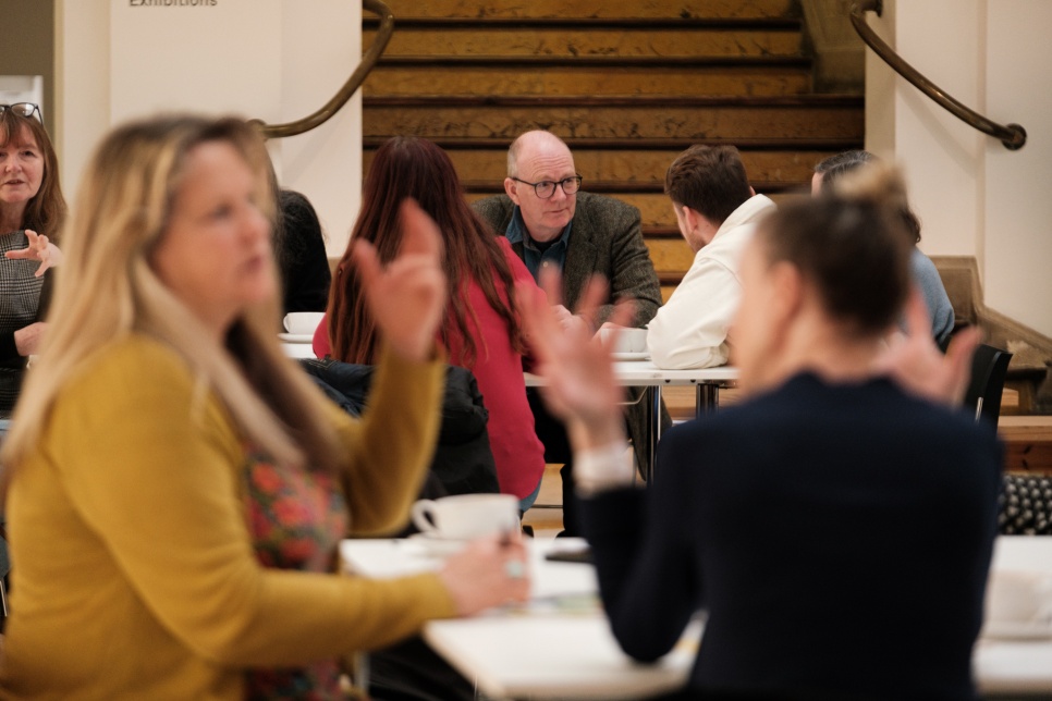 Workshop image of people sat at tables talking