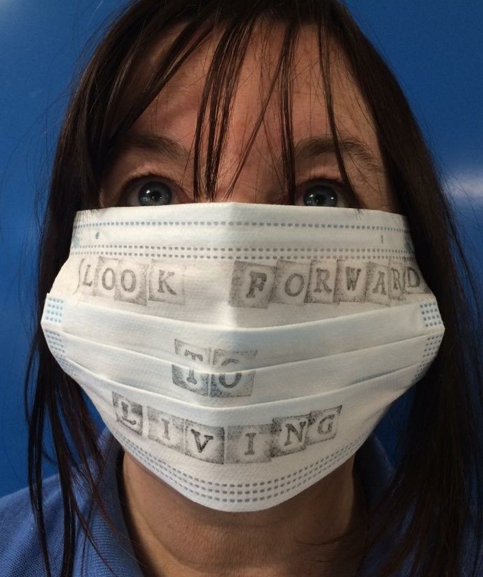 lady with face mask on her with text drawn on saying look forward to living