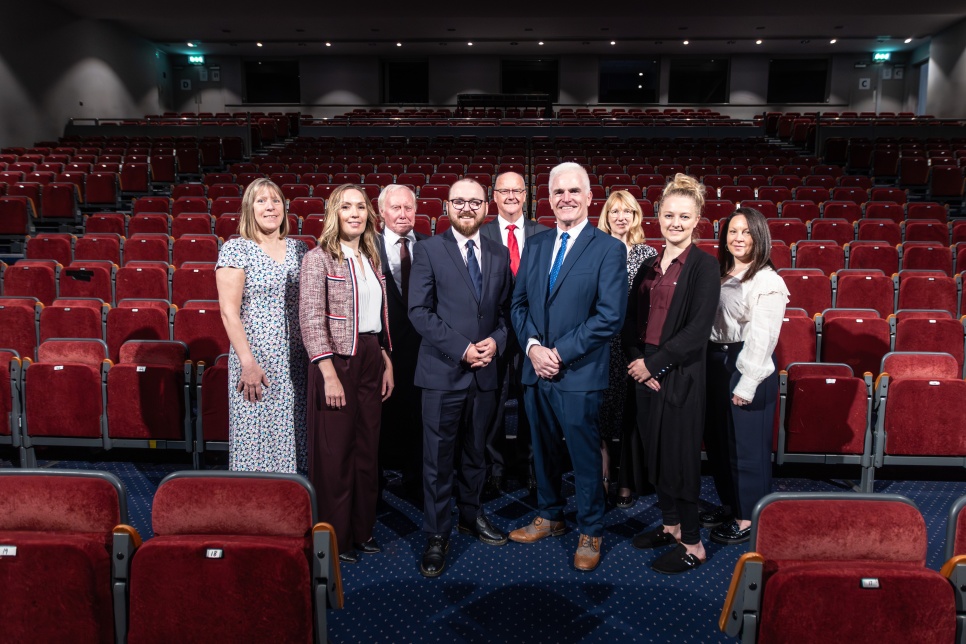 Grwp o bobl yn sefyll mewn theatr