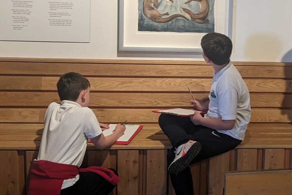 two young boys in an art gallery looking at paintings and drawing